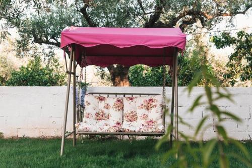 a pink canopy over a chair in the grass at The Mills House in Kallithea