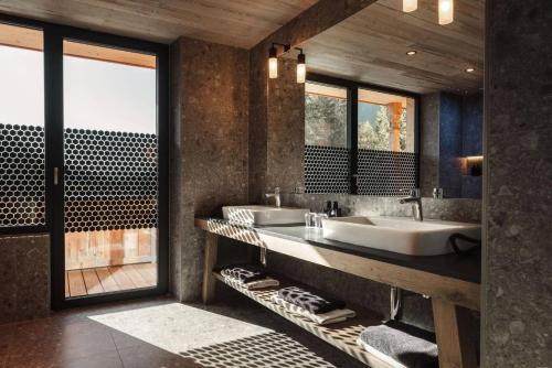 ein Badezimmer mit zwei Waschbecken und einem großen Fenster in der Unterkunft Alpenhotel Kitzbühel am Schwarzsee - 4 Sterne Superior in Kitzbühel