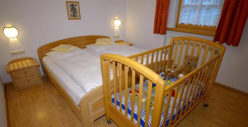 - une chambre avec un lit bébé avec un ours en peluche dans l'établissement Marerhof, à San Candido