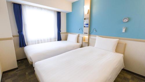 two beds in a room with blue walls and a window at Toyoko Inn Urawa misono eki Higashi guchi in Saitama