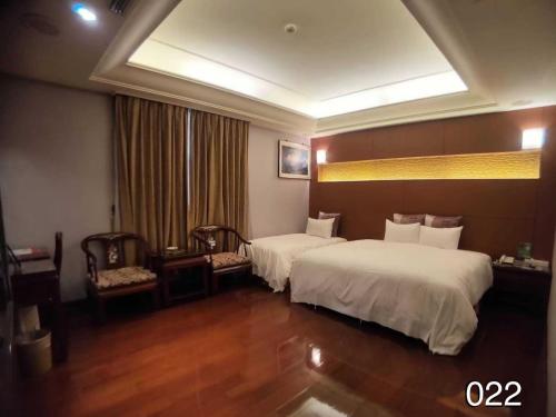 龍潭區的住宿－溫馨汽車旅館，酒店客房带两张床和一张桌子以及椅子。