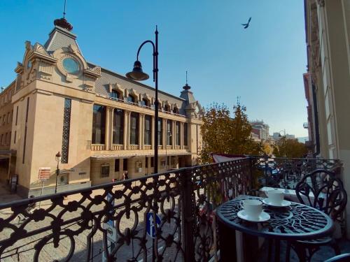 a table with two cups on a balcony with a building at Boutique Hotel Alegria in Tbilisi City