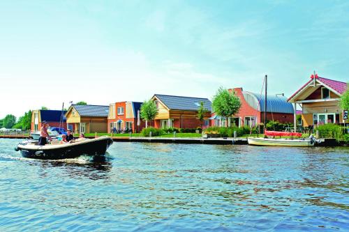 a boat in the water in front of houses at Recreatiepark Tusken de Marren in Akkrum