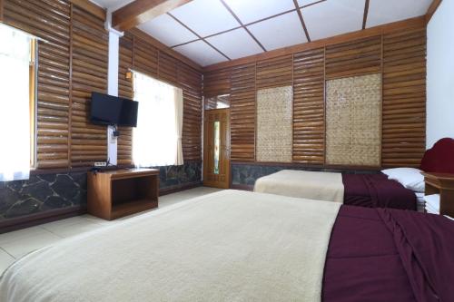 um quarto com 2 camas e uma televisão de ecrã plano em Kampung Pa'go Resort Hotel em Bandung