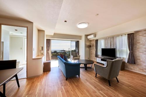 a living room with a television and a table and chairs at Hotel Village Izukogen in Ito