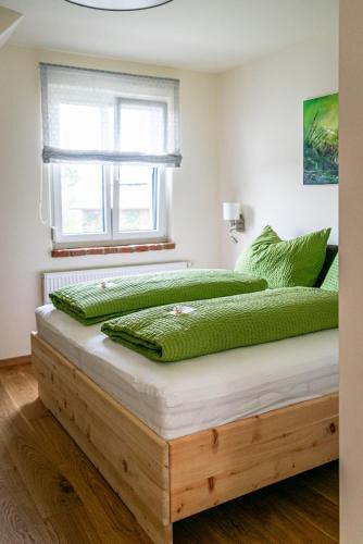 2 Betten mit grünen Kissen in einem Schlafzimmer in der Unterkunft Weinhof Reichmann in Sankt Peter am Ottersbach