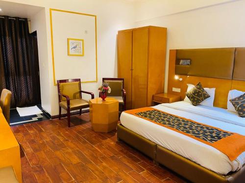 ein Hotelzimmer mit einem großen Bett und Stühlen in der Unterkunft L'ELEGANT Hotel & Banquet in Ghaziabad