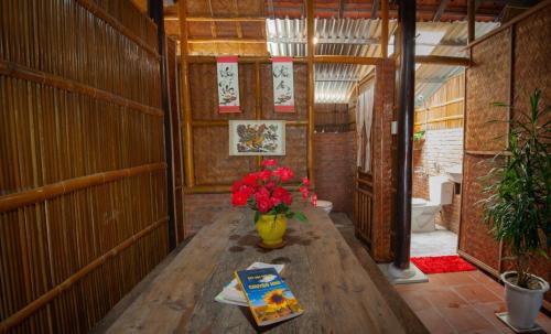 Habitación con mesa de madera y jarrón de flores. en Tra Que Flower Homestay, en Hoi An