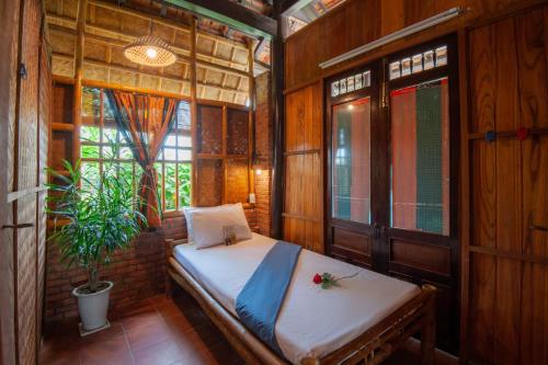 a bedroom with a bed and a plant in it at Tra Que Flower Homestay in Hoi An