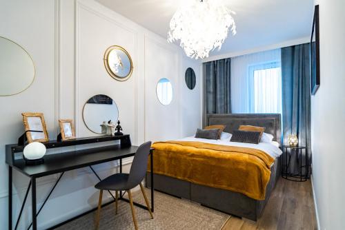 een slaapkamer met een bed, een bureau en een kroonluchter bij ApartamentySnu, Struga Tower Double Gold z parkingiem in Radom