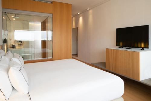 a bedroom with a white bed and a television at Melia Palma Bay in Palma de Mallorca
