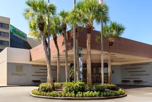 a building with palm trees in front of it at Holiday Inn Orlando International Airport by IHG in Orlando