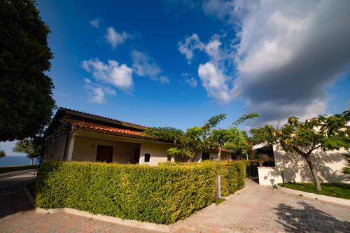 a house with a hedge in front of a street at Residence New Paradise in Tropea