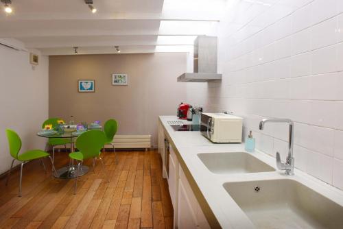 a kitchen with a sink and a table with green chairs at Old Fire Station Canterbury in Canterbury