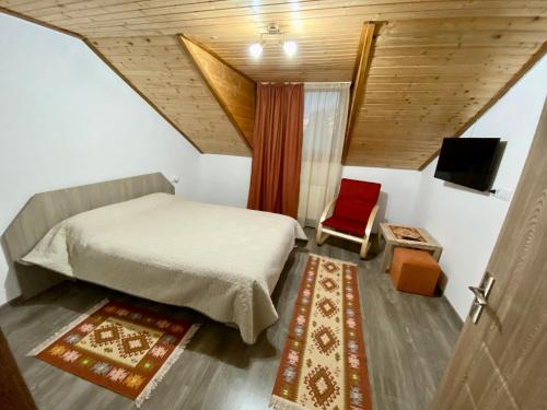 a bedroom with a bed and a red chair at Casa Mis in Baia de Fier