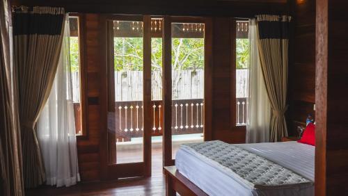 - une chambre avec un lit et des portes coulissantes en verre dans l'établissement Madaira Villa Senggigi by The Lavana, à Mangsit