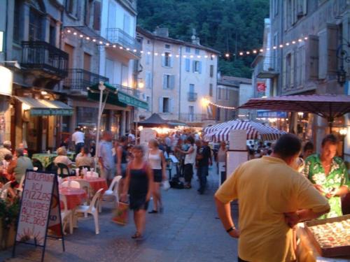 una multitud de personas caminando por una calle de la ciudad por la noche en Gîte largentiere, en Largentière