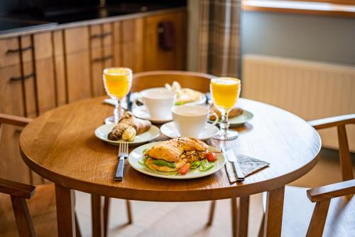 a table with plates of food and glasses of orange juice at Palanga Visit Apartments and SPA in Palanga