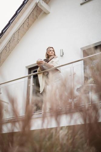 a woman is standing on a glass railing at Apartamenty u Harrego II Przy Stawie Spa klimatyzacja,balkon,sauna , balia, ogród,parking in Kudowa-Zdrój