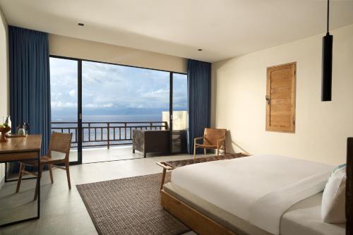 a bedroom with a bed and a desk and a balcony at Adiwana Warnakali Resort in Nusa Penida