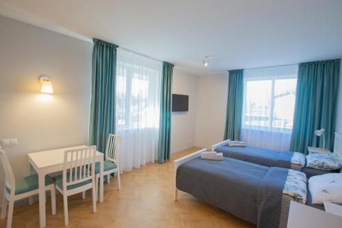 a bedroom with two beds and a table and a desk at Apartamentai Baltas gandras in Naisiai