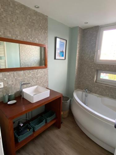 La salle de bains est pourvue d'une baignoire, d'un lavabo et d'un miroir. dans l'établissement Appartement situé en centre ville super lumineux, à Dunkerque