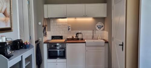a small kitchen with white cabinets and a stove at Slapen bij Bonanza in Bantega