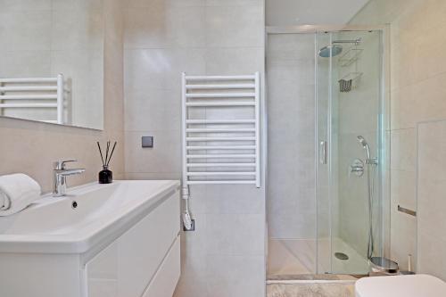 Un baño blanco con lavabo y ducha. en Sky Beach Apartment, en Quarteira