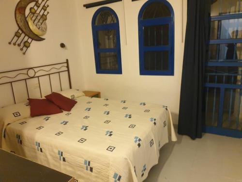 ein Schlafzimmer mit einem Bett und blauen Fenstern in der Unterkunft Apartamento situado en Maspalomas in Las Palmas de Gran Canaria