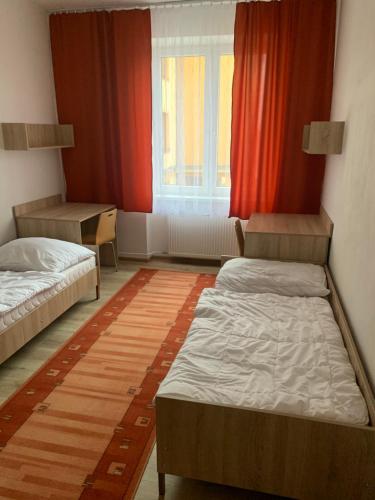 a room with two beds and a window with red curtains at Hostel SOS Moldava in Moldava nad Bodvou