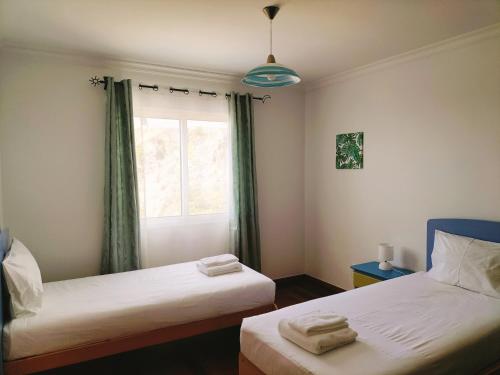 two beds in a room with a window at Villa Fanny in Ribeira Brava