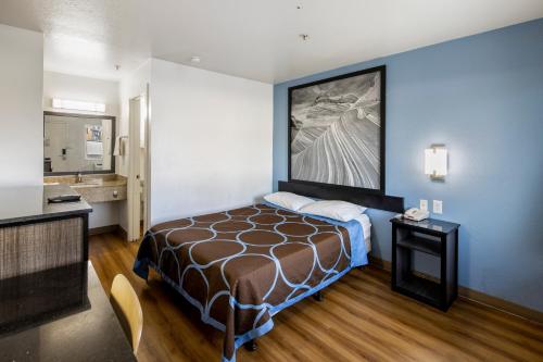 a hotel room with a bed and a large painting on the wall at Super 8 by Wyndham Phoenix West in Phoenix