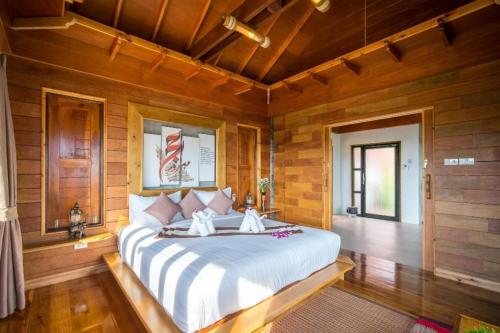 a bedroom with a large bed in a room with wooden walls at Puteri Lanta Family Villas in Ko Lanta