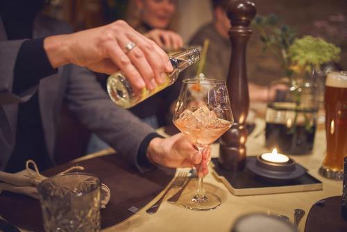 a person is pouring a drink into a glass at Bauernhof Hotel Oberschwarzach in Saalbach Hinterglemm