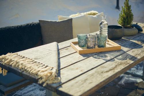 a wooden table with four glasses and a bottle on it at Bauernhof Hotel Oberschwarzach in Saalbach Hinterglemm