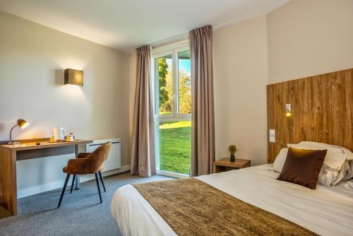 a hotel room with a bed and a desk and a window at Les Jardins de l'Anjou in La Pommeraye