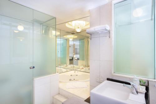 a bathroom with a sink and a shower and a tub at Lux Tychi Hotel in Malang