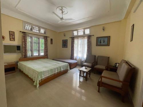 a bedroom with a bed and a couch and a chair at The Choudhury Manor Homestay in Guwahati