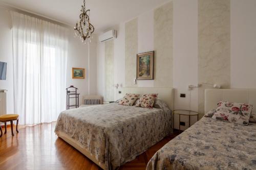 1 dormitorio con 2 camas y lámpara de araña en La Spezia Holidays, en La Spezia