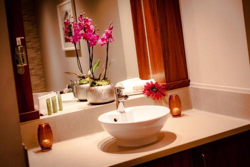 a bathroom with a sink and flowers on a counter at Manchester Piccadilly Hotel in Manchester