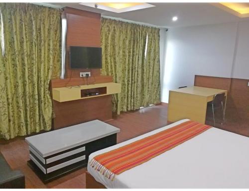 a bedroom with a bed and a desk and a television at Hotel SPS Inn, Rewa in Rewa