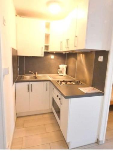 une petite cuisine avec des armoires blanches et un évier dans l'établissement Beija Flor, au Cap d'Agde