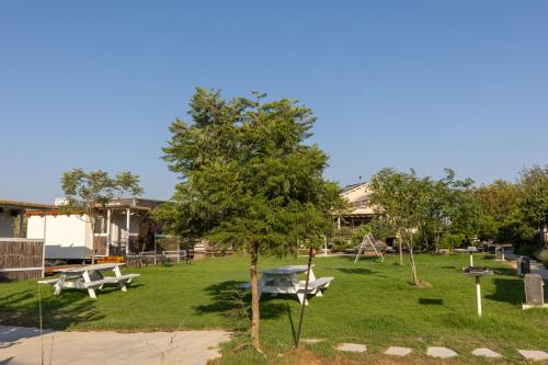 a park with two picnic tables and a tree at אצלנו בחצר in Avnei Eitan