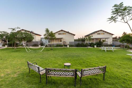 two park benches in a yard with a playground at אצלנו בחצר in Avnei Eitan