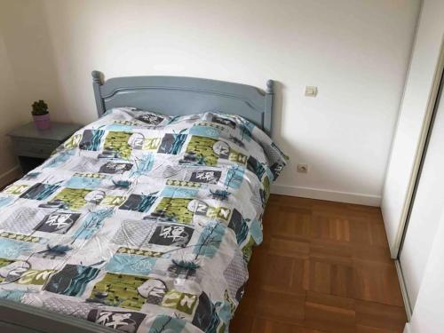 een slaapkamer met een bed met een dekbed erop bij Appartement 55m2 en beaujolais & ENEDIS à 15 min in Saint-Germain-Nuelles