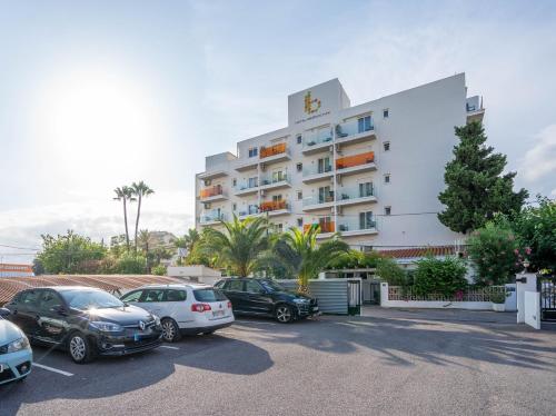 a large white building with cars parked in a parking lot at Hotel Bersoca in Benicàssim