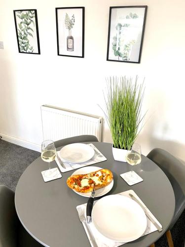 a table with a pizza and two glasses of wine at HU-Thirteen Apt Two- Sleeps 4 in Hessle