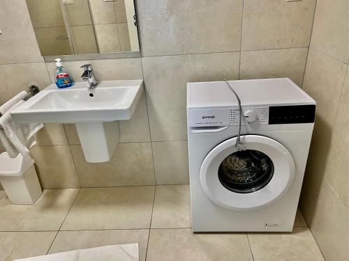 a bathroom with a washing machine next to a sink at Apartman Balaton in Keszthely