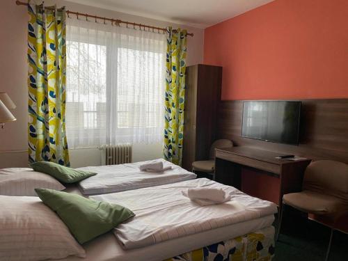 a room with two beds and a desk and a television at Hotel Formanka in Hustopeče