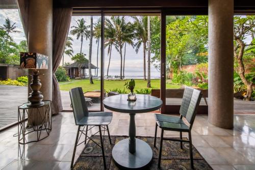 a patio with a table and chairs and a view of the ocean at Villa Manis Beachfront Candidasa in Candidasa